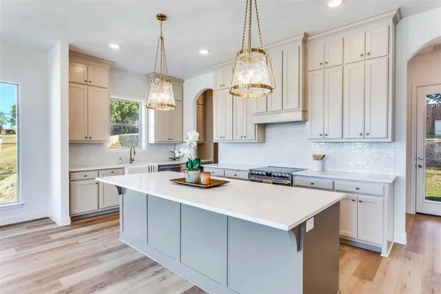 a view of a kitchen with granite countertop stainless steel appliances refrigerator a sink and a fireplace