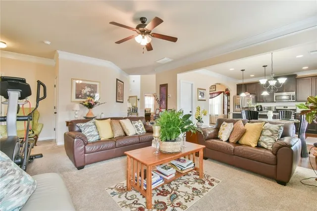 a living room with furniture kitchen view and a chandelier