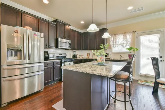 a kitchen with stainless steel appliances granite countertop a sink refrigerator and cabinets