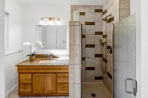 a bathroom with a granite countertop sink a mirror and shower