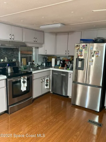 a kitchen with stainless steel appliances granite countertop a stove a sink and white cabinets