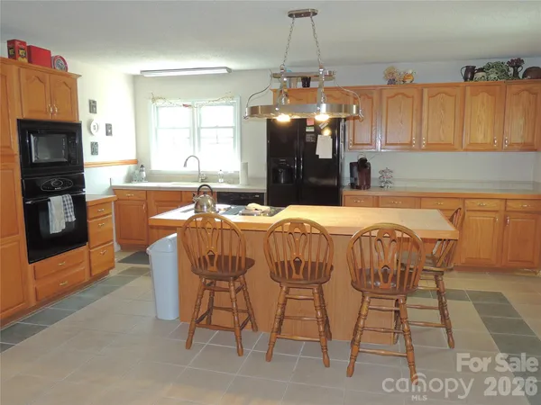 a dining room with furniture a chandelier and kitchen view