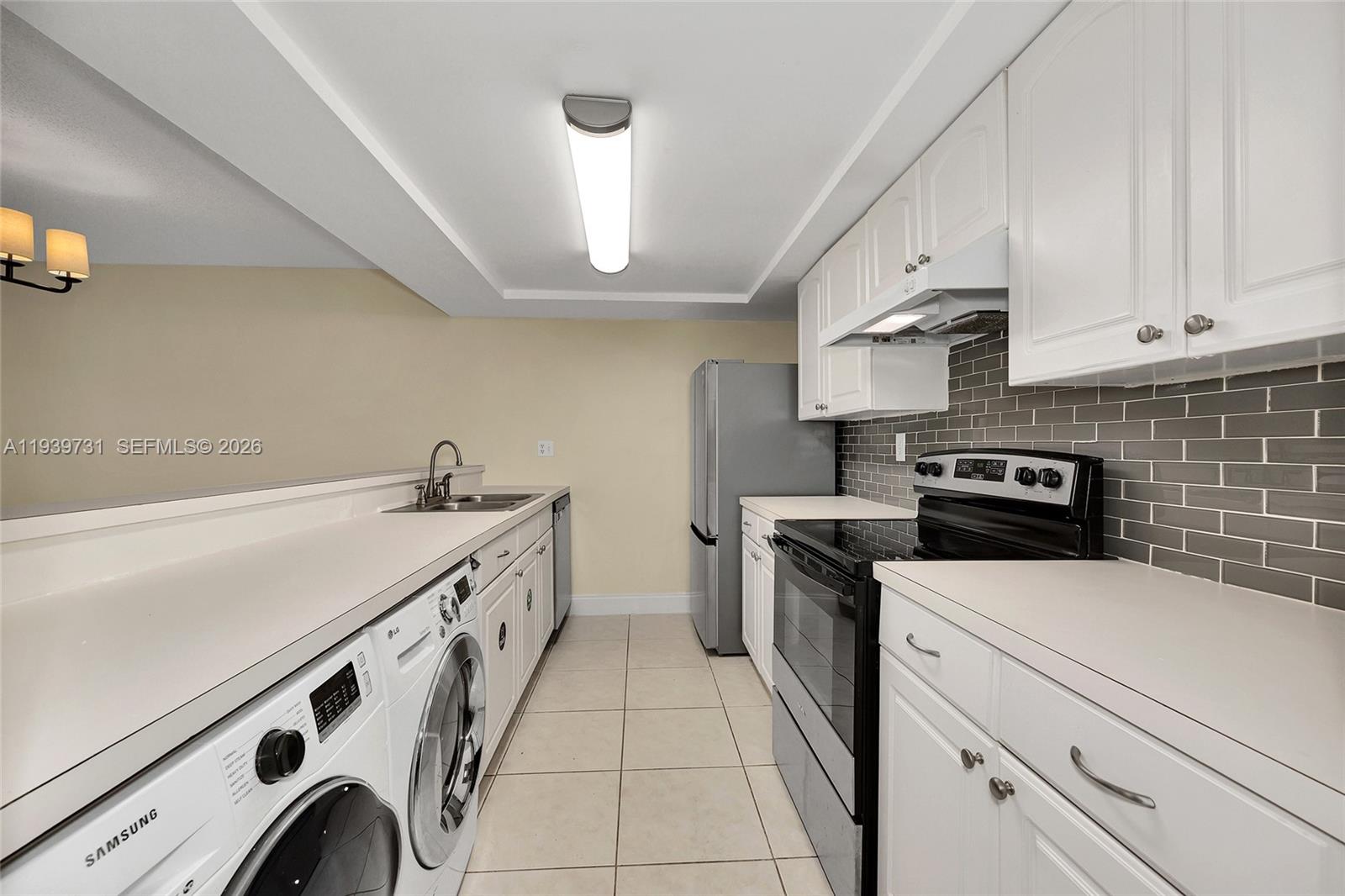 9079 Southwest 133rd Court, Unit F Miami, FL 33186 - Photo 11 of 34 a kitchen with stainless steel appliances a sink dishwasher stove and white cabinets with wooden floor