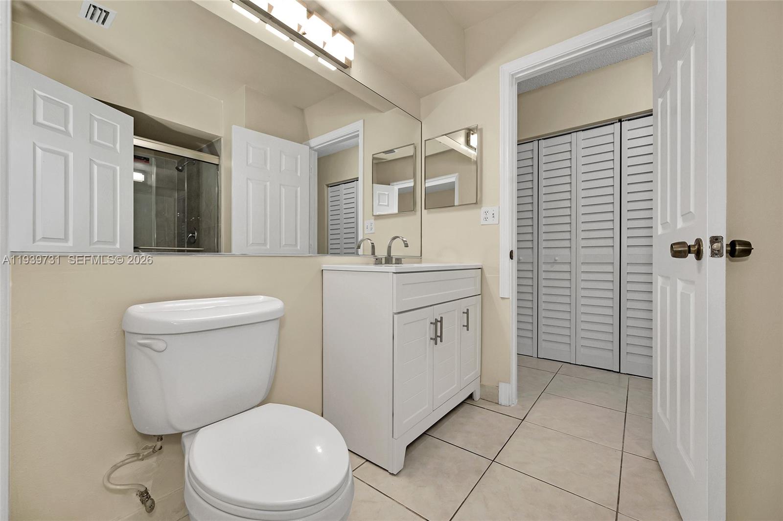 9079 Southwest 133rd Court, Unit F Miami, FL 33186 - Photo 24 of 34 a bathroom with a toilet sink vanity and mirror