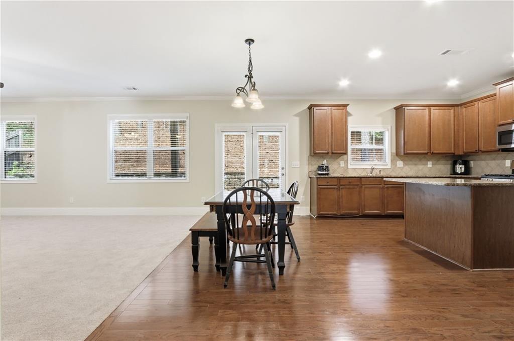 1515 Riva Ridge Suwanee, GA 30024 - Photo 8 of 35 a kitchen with stainless steel appliances granite countertop a stove top oven a dining table and chairs with wooden floor