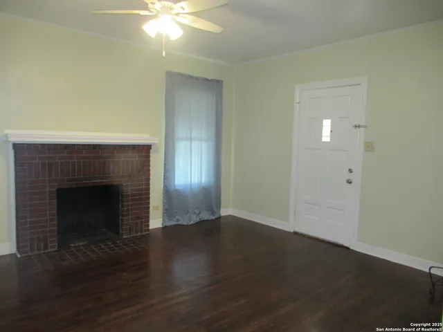 a view of an empty room with wooden floor and a fireplace