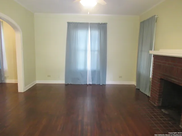 an empty room with wooden floor and fireplace