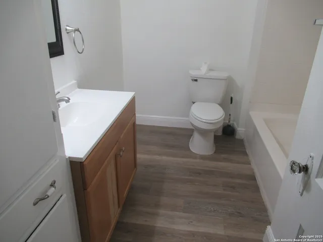 a bathroom with a sink toilet and a wooden floor