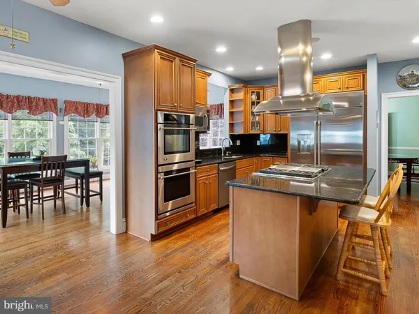 a kitchen with stainless steel appliances kitchen island granite countertop a stove refrigerator and cabinets