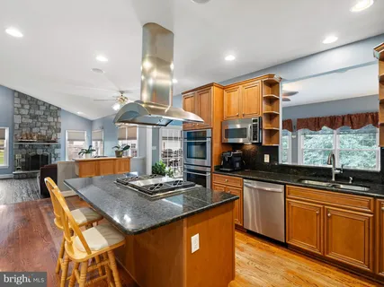 a kitchen with stainless steel appliances kitchen island granite countertop a stove refrigerator and cabinets