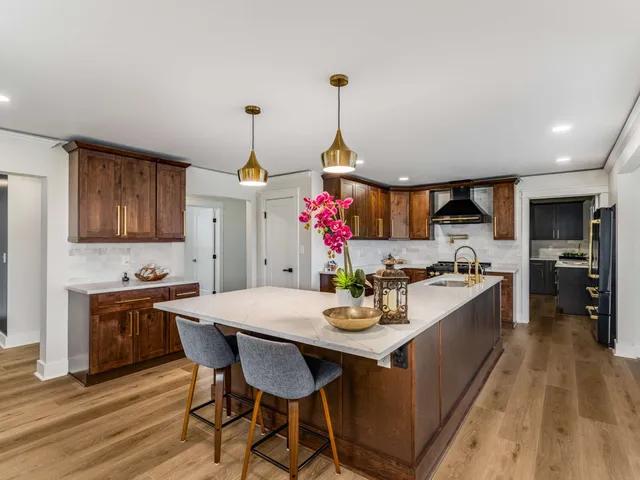 a kitchen that has a sink and a stove with wooden floor