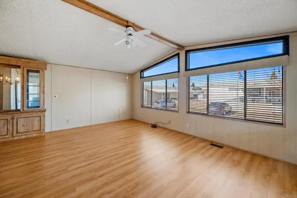 a view of an empty room with a window and wooden floor