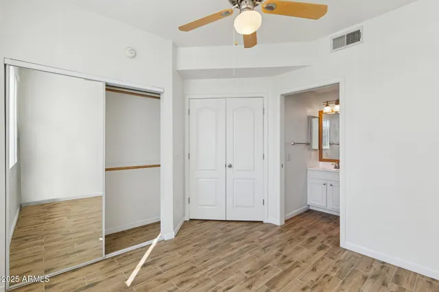 a view of an empty room with wooden floor and a fan