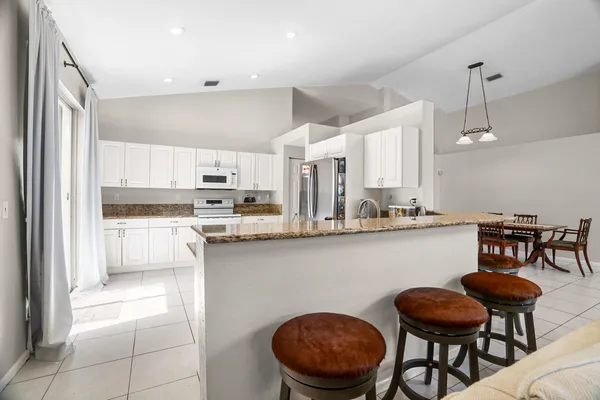 a kitchen with stainless steel appliances granite countertop a table chairs sink and cabinets