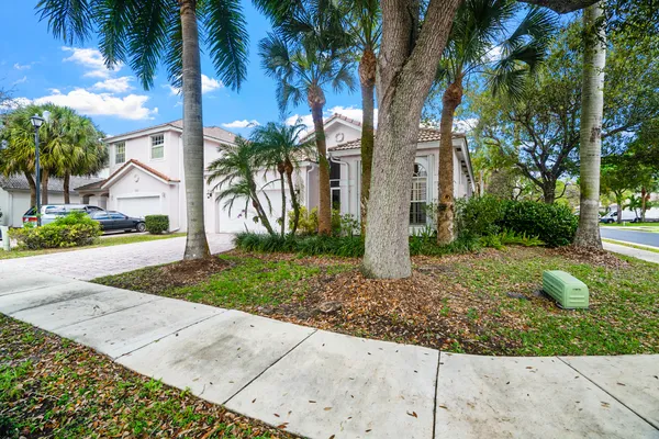 a front view of a house with a yard and palm trees