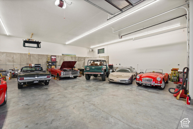 5878 Snowbasin Road Huntsville, UT 84317 - Photo 64 of 90 Expansive garage with concrete flooring, multiple overhead garage doors, high ceilings, and fluorescent lighting
