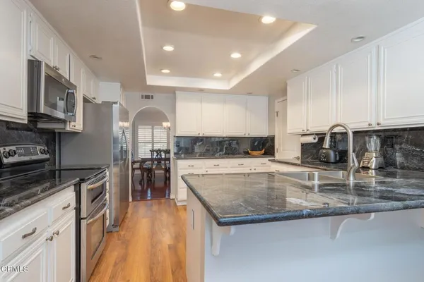 a kitchen with stainless steel appliances granite countertop a stove top oven a sink a dining table and chairs