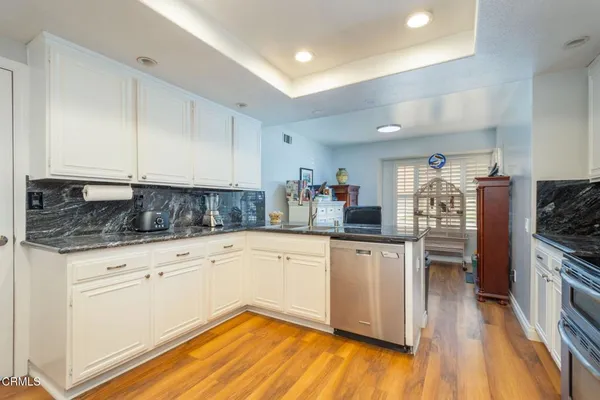 a kitchen with granite countertop white cabinets and white appliances