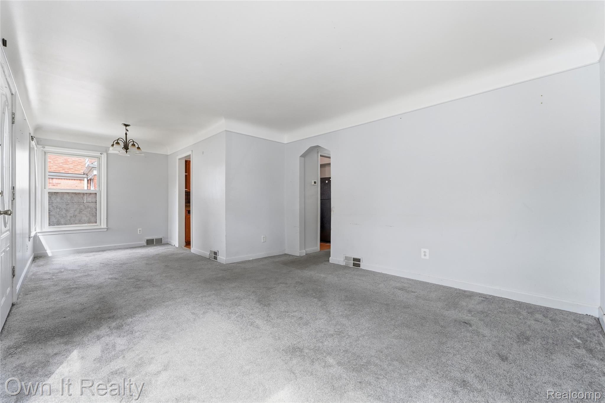 3331 Harding Street Dearborn, MI 48124 - Photo 6 of 31 Light gray wall paint, gray carpeting, a single window, a ceiling-mounted light fixture, and an arched doorway