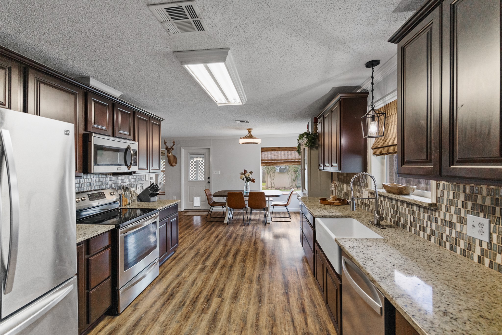 1003 Virginia Street Edna, TX 77957 - Photo 9 of 30 a kitchen with granite countertop stainless steel appliances a stove top oven a sink dishwasher a dining table and chairs with wooden floor