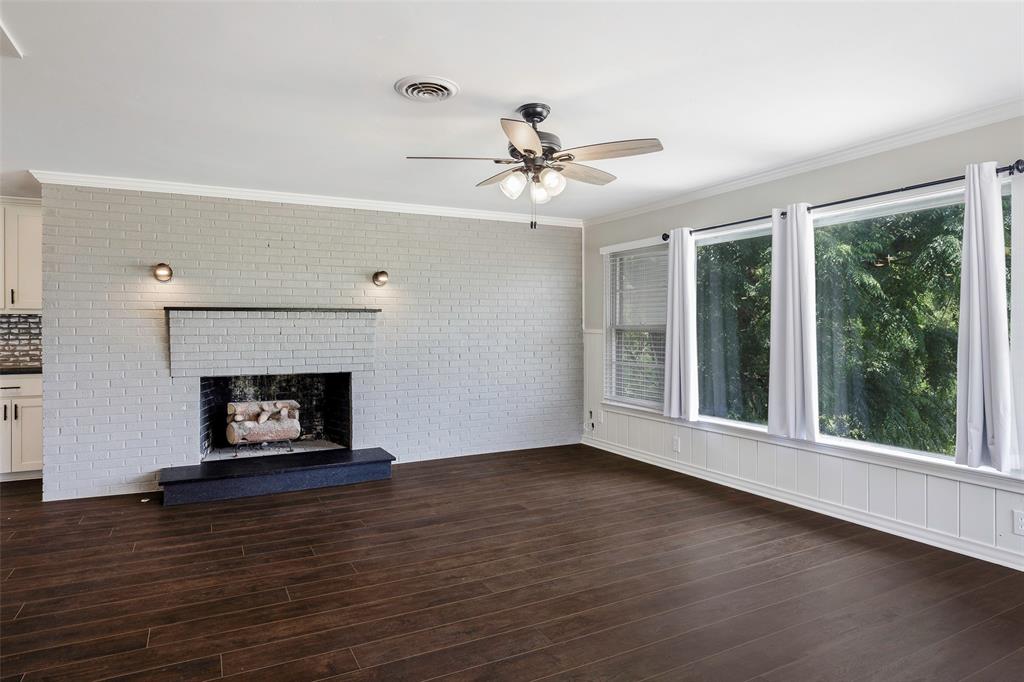 2323 Sutter Street Dallas, TX 75216 - Photo 12 of 30 Unfurnished family room featuring dark hardwood / wood-style flooring, ceiling fan, a fireplace, and crown molding