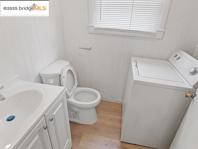 1655 East 32nd Street, Unit 1655 Oakland, CA 94602 - Photo 11 of 12 Bathroom featuring vanity, light wood-type flooring, washing machine and clothes dryer, and wooden walls