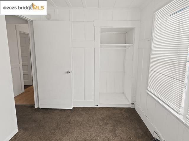 1655 East 32nd Street, Unit 1655 Oakland, CA 94602 - Photo 12 of 12 Unfurnished bedroom with dark colored carpet, a closet, and a decorative wall