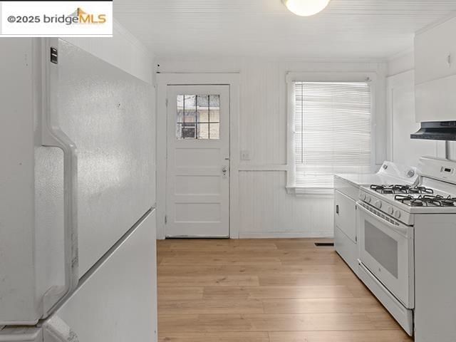1655 East 32nd Street, Unit 1655 Oakland, CA 94602 - Photo 9 of 12 Kitchen featuring white appliances, light wood-style flooring, washer / dryer, white cabinets, and under cabinet range hood