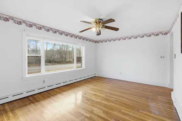 a view of a room with wooden floor fan and windows