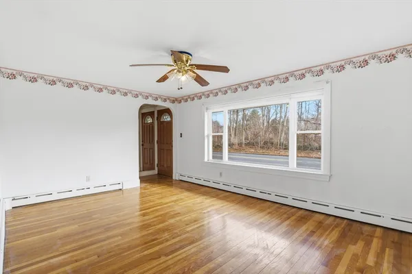 a view of an empty room with a window and wooden floor