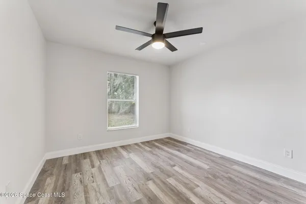 an empty room with a window and a ceiling fan