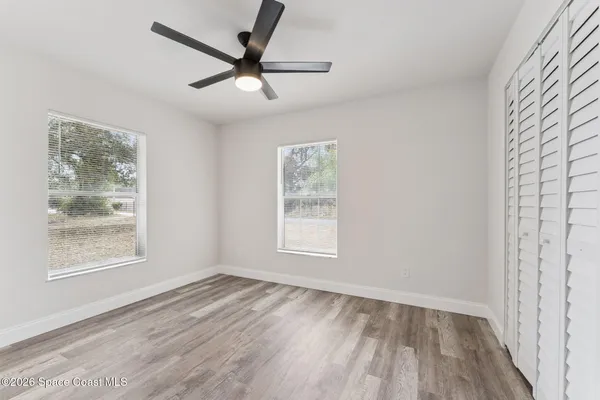 a view of empty room with wooden floor and fan