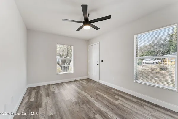 a view of empty room with wooden floor and fan