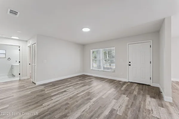 a view of an empty room with wooden floor and a window