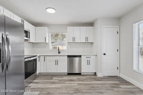 a kitchen with granite countertop a refrigerator stove top oven and sink