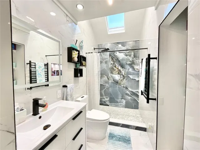 a large white kitchen with a stove a sink dishwasher and a dining table with the kitchen view