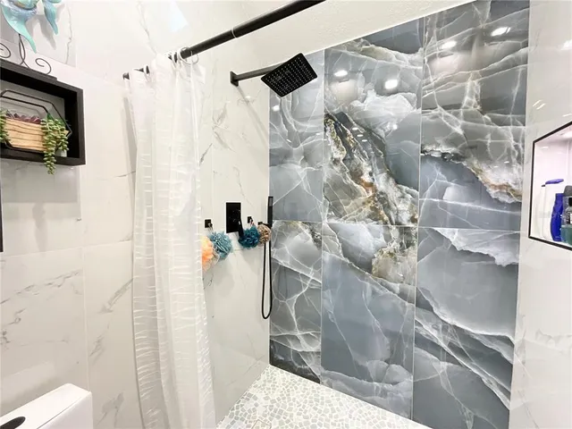 a large white kitchen with stainless steel appliances kitchen island granite countertop a table and a chandelier