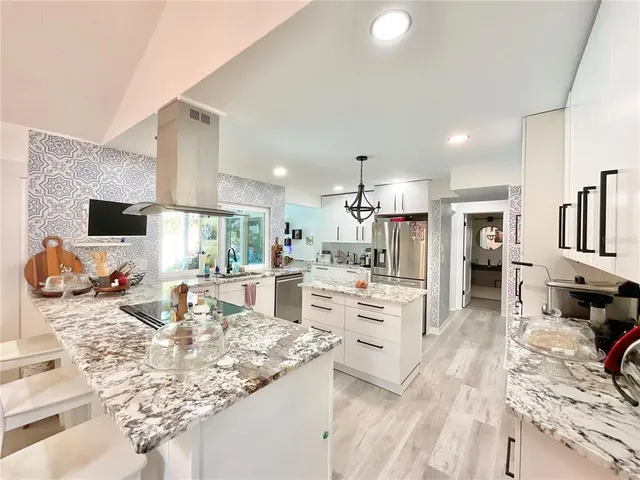 a kitchen with a stove a sink dishwasher a dining table and chairs with wooden floor