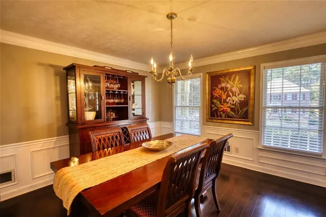 a dining room with wooden floor a chandelier a wooden table and chairs