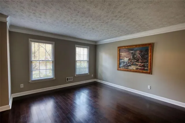 an empty room with wooden floor and windows with curtains view