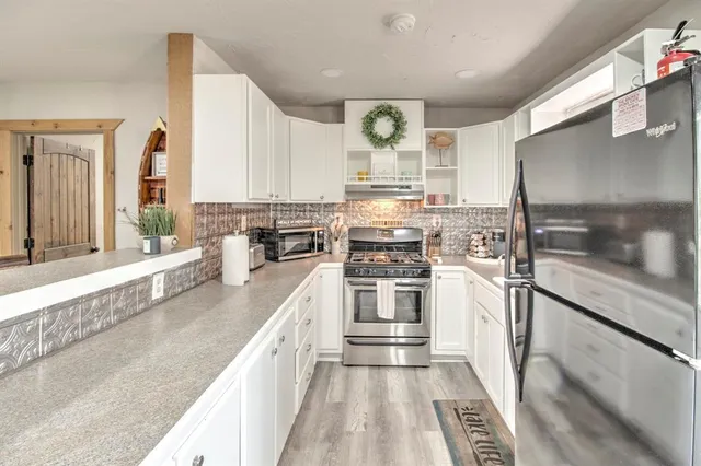 a view of a kitchen with a sink and dishwasher stove a refrigerator a oven with wooden floor