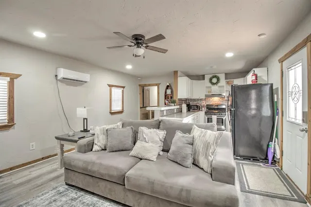 a living room with stainless steel appliances furniture and a view of kitchen