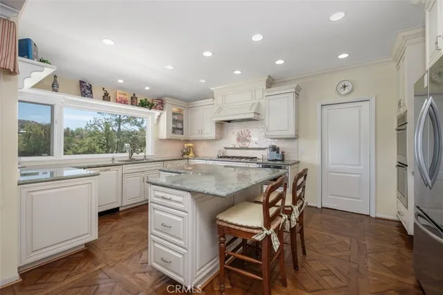 a kitchen with stainless steel appliances granite countertop a table chairs sink refrigerator and cabinets