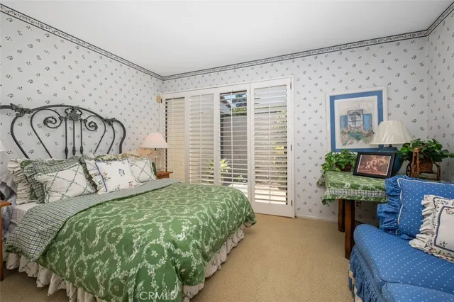 a bedroom with a bed a couch and potted plant on the dresser
