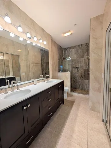 a spacious bathroom with a double vanity sink a mirror and a shower