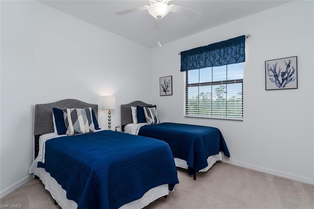 9596 Trevi Court, Unit 5431 Naples, FL 34113 - Photo 16 of 32 a bedroom with two beds and a chandelier
