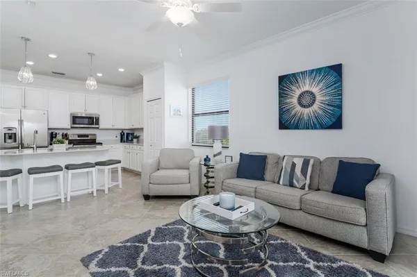 a living room with furniture kitchen view and a chandelier