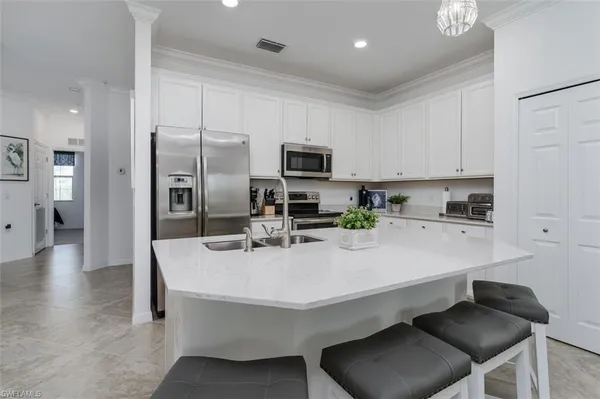 a kitchen with stainless steel appliances a sink a stove a refrigerator cabinets and chairs