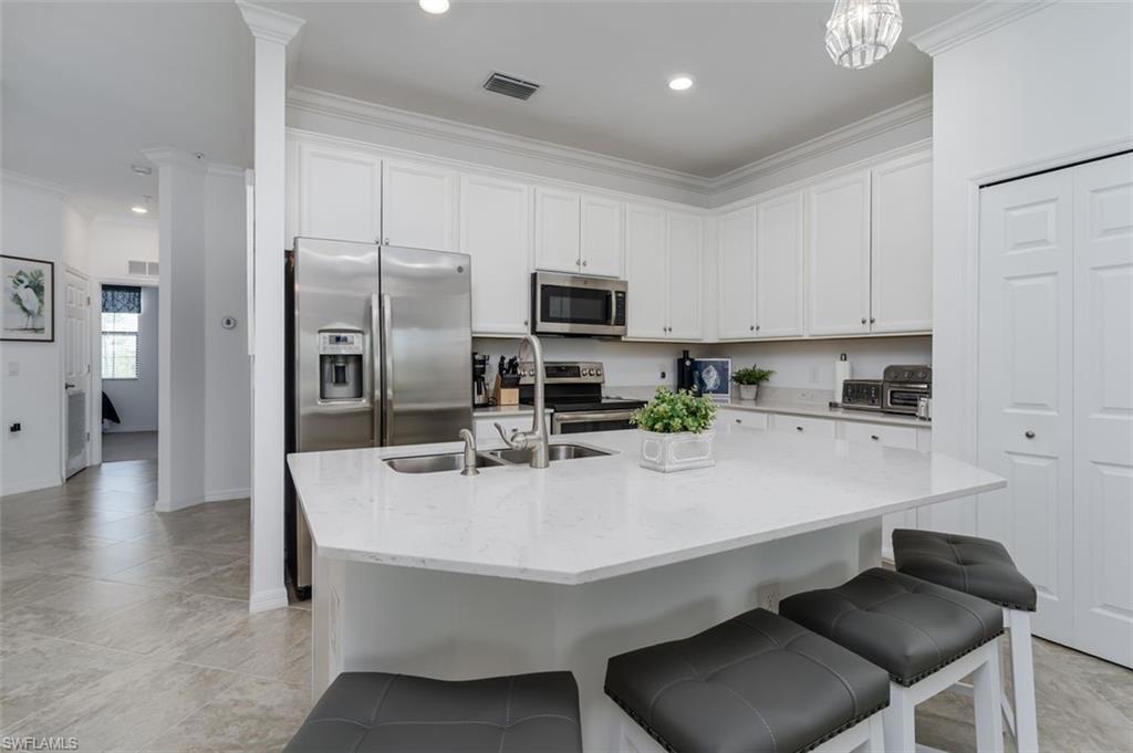 9596 Trevi Court, Unit 5431 Naples, FL 34113 - Photo 6 of 32 a kitchen with stainless steel appliances a sink a stove a refrigerator cabinets and chairs