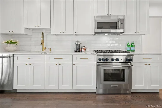 a kitchen with white cabinets and stainless steel appliances